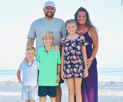 A family standing on the beach smiling at the camera